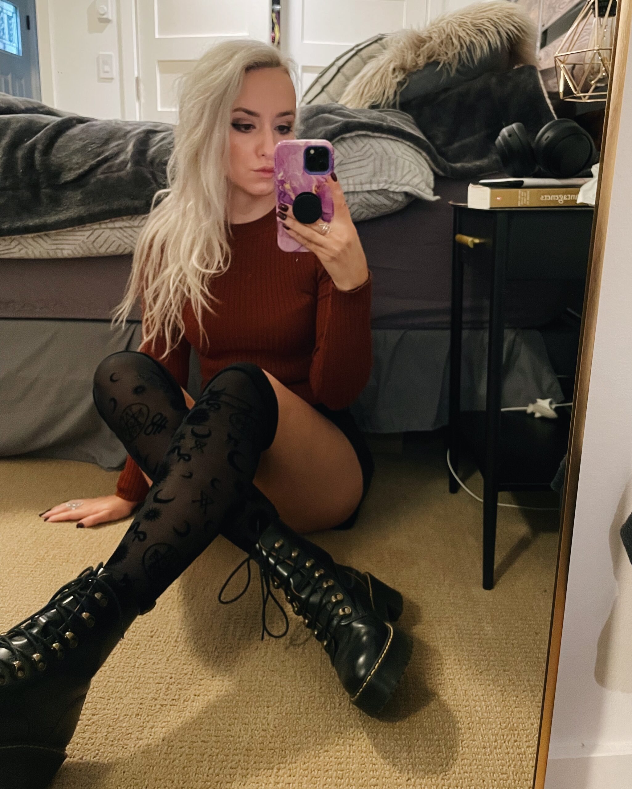 Blonde wearing a fall outfit, burnt orange top and sheer knee high boots