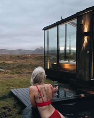 Looking out from a hot tub next to a glass roof cabin with the bare Icelandic wilderness in the distance