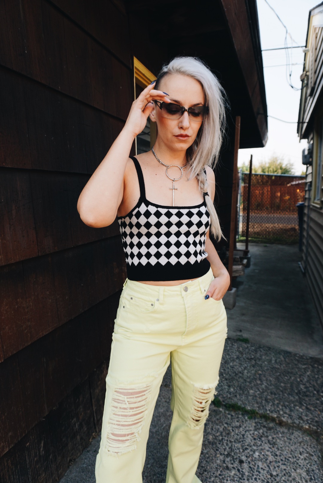 A woman wearing a black and white checkered tank top and neon yellow jeans